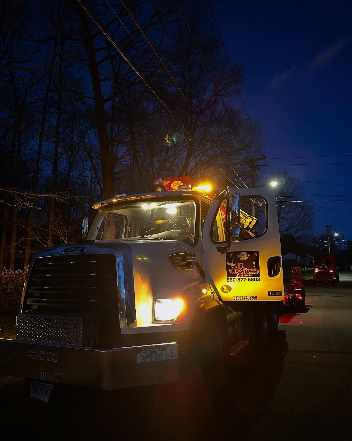 USA Tree Experts service truck at night with yellow hazard lights flashing during an emergency tree removal call in Connecticut.